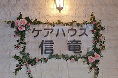 扉の横には、バラの花で飾られ、来館者の方の目を引く看板があります。